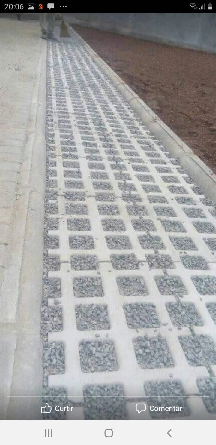 Faixa de concregrama com aberturas preenchidas por agregado, junto a muro.