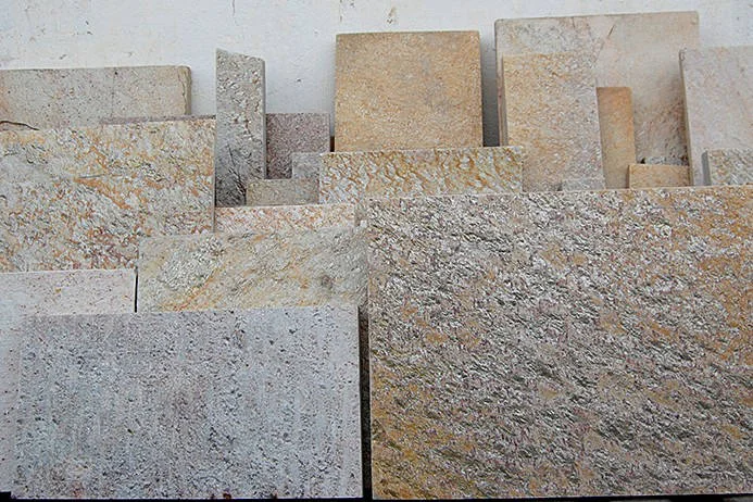 Placas retangulares de pedra em tons amarelos, bege e cinza, apoiadas lado a lado.
