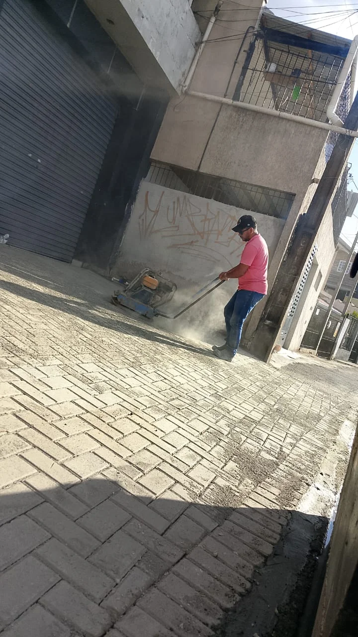 Operador com equipamento de compactação sobre piso de peças.